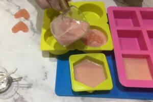 pouring liquid soap base around a soap embed in a soap mould