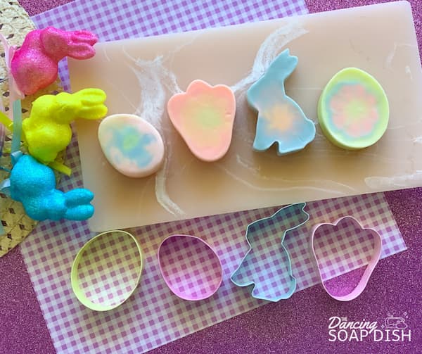 four easter soap bars sitting alongside four easter cookie cutters of the same shape