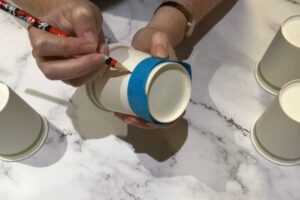 tracing a template shape onto a paper cup with a pencil