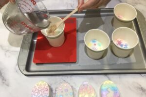 pouring a clear layer of soap onto a painted egg soap