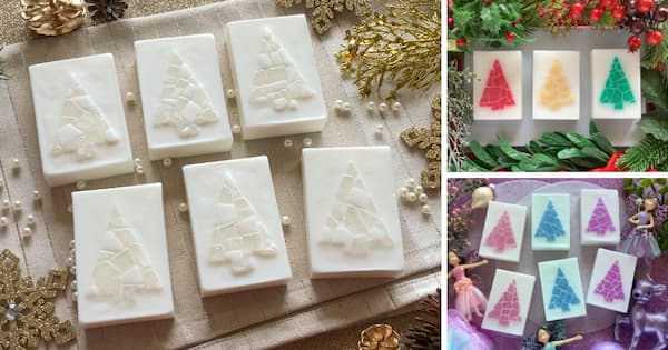 Rectangular Christmas themed soap bars with embossed mosaic Christmas tree designs are displayed in a festive arrangement. On the left, eight white soaps with silvery white Christmas trees sit on a beige cloth with gold accents. On the right, two smaller sections show colourful versions featuring red, gold and green Christmas trees surrounded by holiday greenery, and glittery pink, blue, and purple trees surrounded by ornaments, and sugar plum fairy figurines.