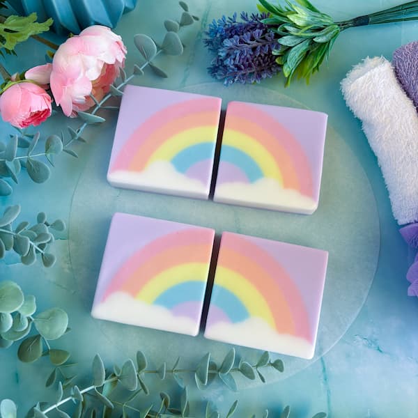 four square melt and pour soap bars with half a pastel rainbow disappearing into a white cloud.