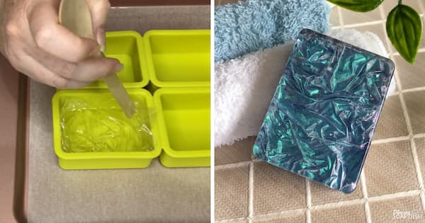 A side‑by‑side collage demonstrating a melt and pour soap technique. On the left, a hand uses a spoon to press down a piece of cling film on top of clear soap inside a bright green silicone mould cavity, creating a crinkled texture. On the right, a finished rectangular soap bar in deep blue and teal tones displays a shimmering crushed‑velvet effect with reflective folds and wrinkles across the surface. Soft towels and green leaves surround the finished soap, creating a spa‑style presentation.